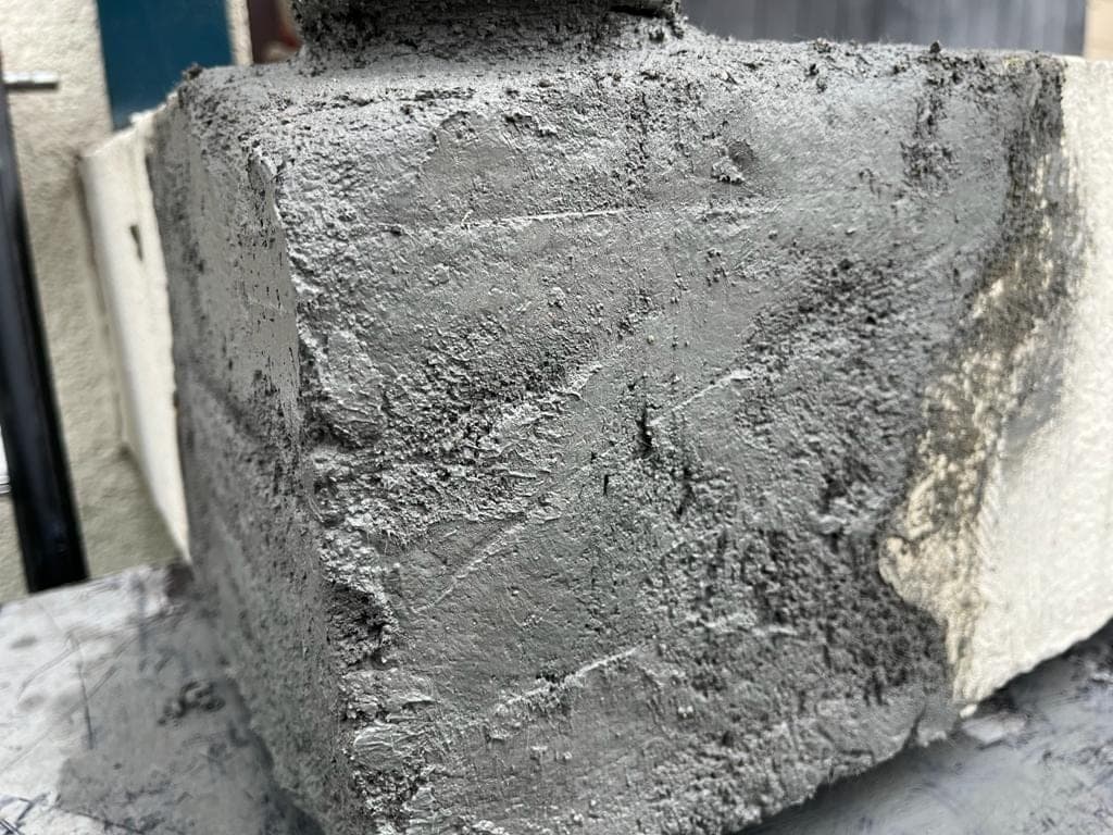 Betonhoek met verse reparatiemortel na het herstellen van betonrot